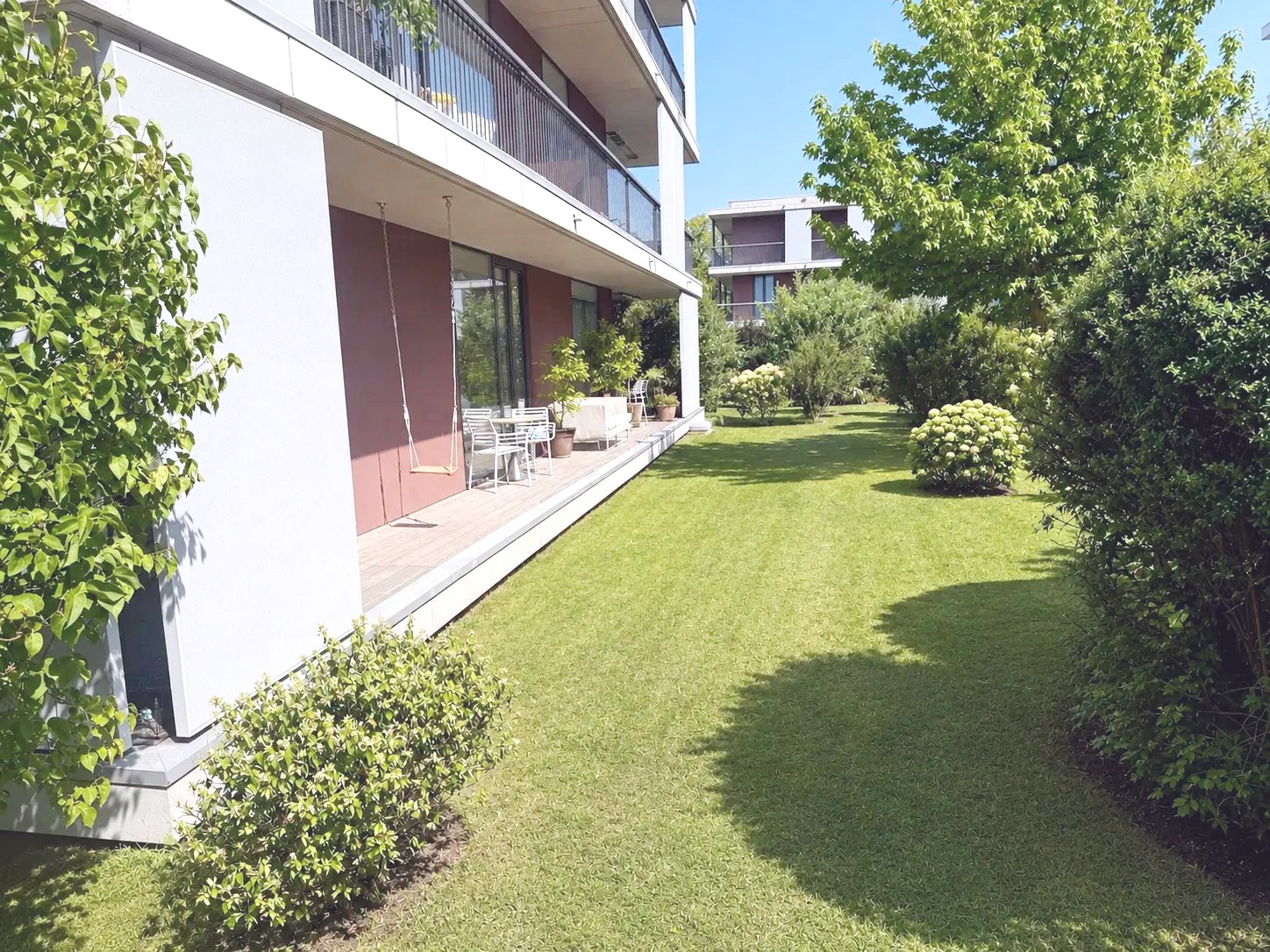 Eigener Garten entlang der Wohnung mit Terrasse und Schaukel
